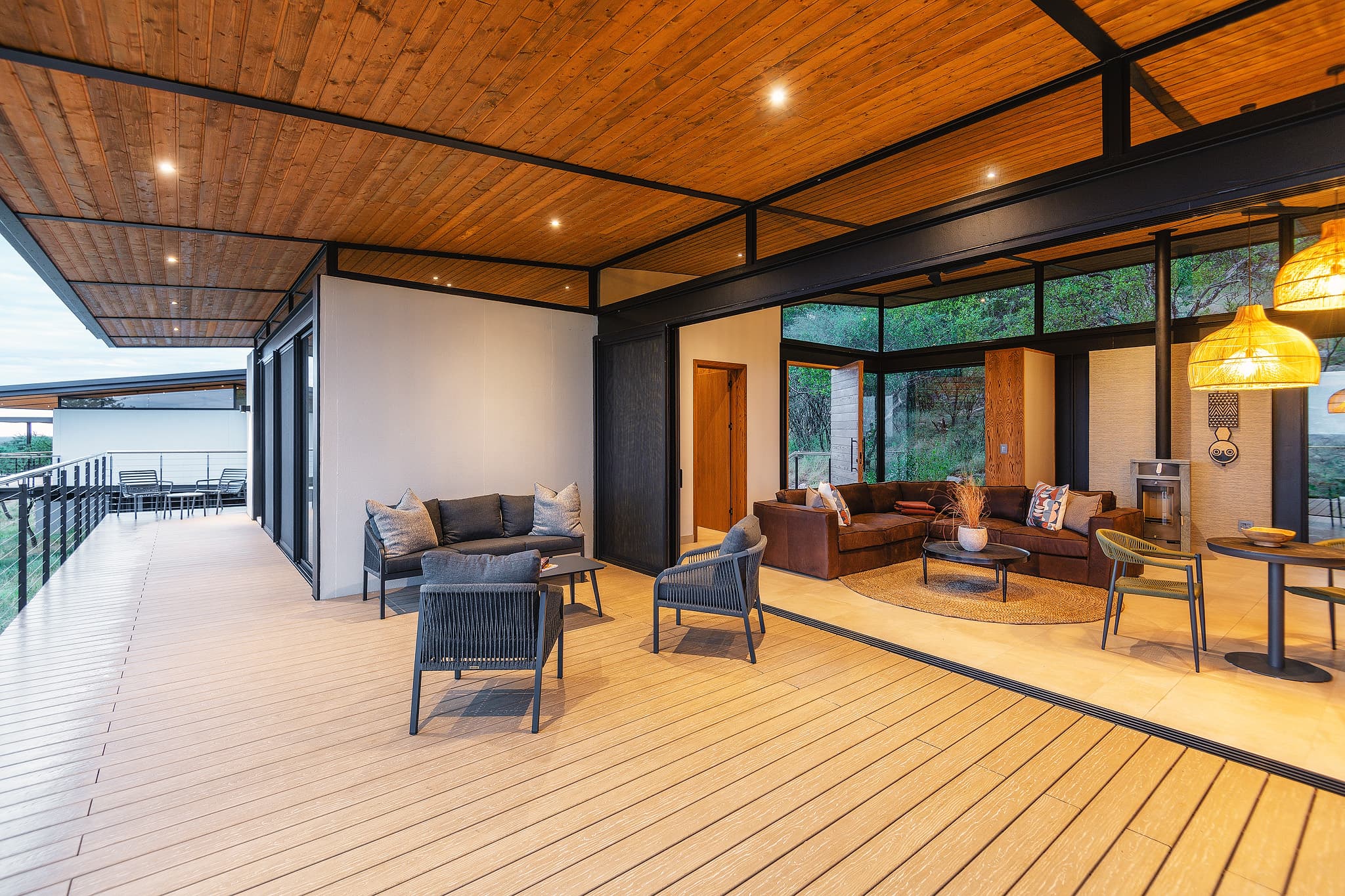 Modern indoor-outdoor living space with a large wooden deck, contemporary furniture, and wood-paneled ceilings.